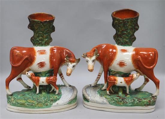 A pair of large Staffordshire pottery cow spill vases